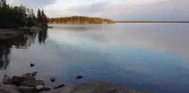 A lake with an island in the distance and rocks along the shore